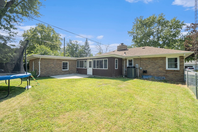 back of property featuring a patio area, a yard, central AC unit, and a trampoline