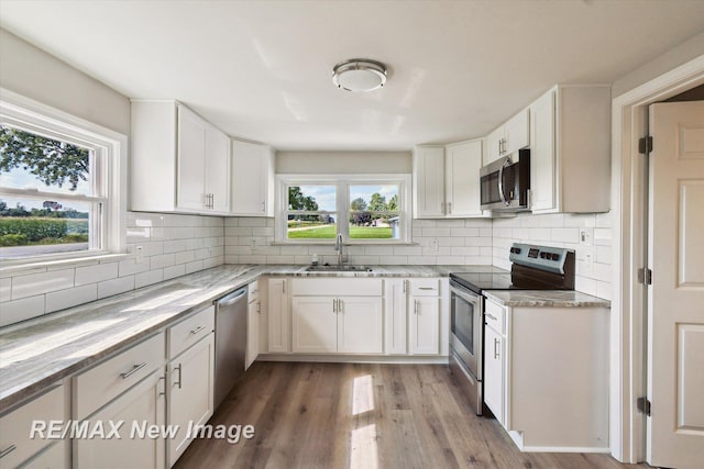 kitchen featuring decorative backsplash, appliances with stainless steel finishes, sink, white cabinets, and hardwood / wood-style floors