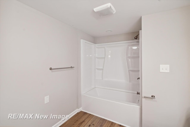 bathroom featuring washtub / shower combination and wood-type flooring