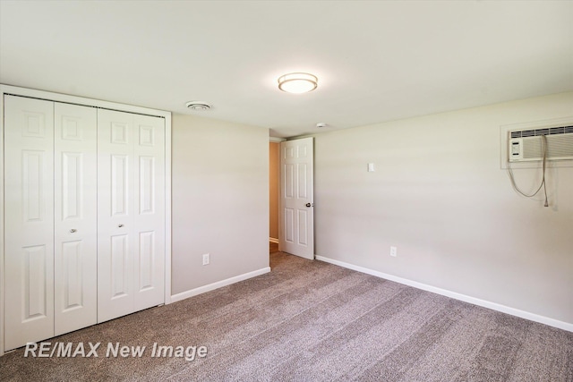 unfurnished bedroom featuring carpet, a wall unit AC, and a closet