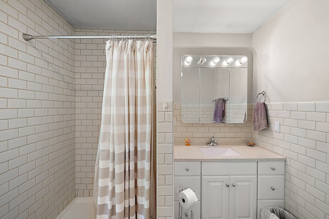 bathroom featuring vanity, curtained shower, and tile walls