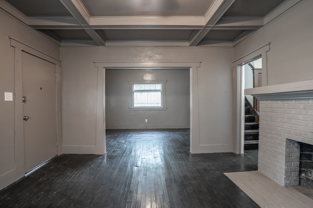 entryway featuring beam ceiling, dark wood-type flooring, coffered ceiling, and a brick fireplace