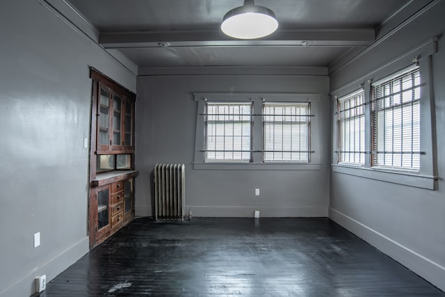 spare room with beamed ceiling, dark hardwood / wood-style flooring, radiator, and ornamental molding