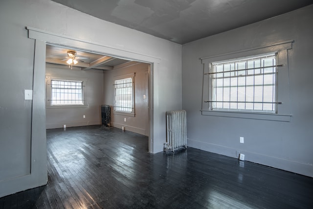 empty room featuring a wealth of natural light, radiator, dark wood-type flooring, and ceiling fan