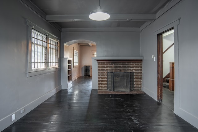 unfurnished living room with dark hardwood / wood-style floors, beam ceiling, ornamental molding, and a fireplace