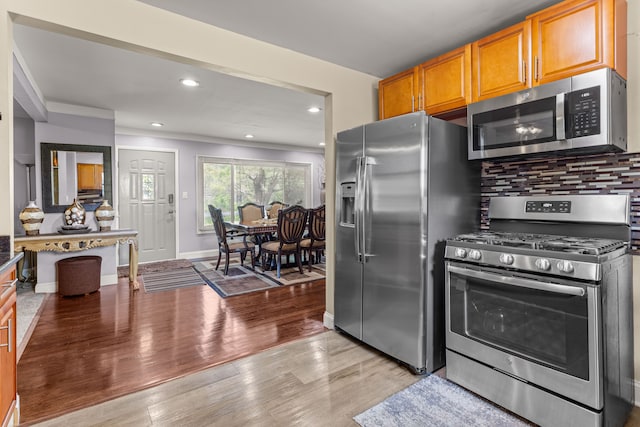 kitchen with backsplash, stainless steel appliances, and light wood-type flooring