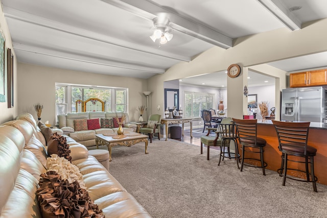 carpeted living room with ceiling fan and beamed ceiling