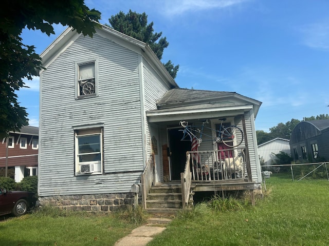 view of front facade with a porch, a front yard, and cooling unit