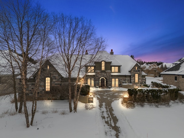 french country home featuring a garage and stone siding