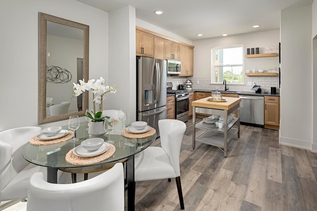 kitchen with decorative backsplash, appliances with stainless steel finishes, light brown cabinetry, dark wood-type flooring, and sink