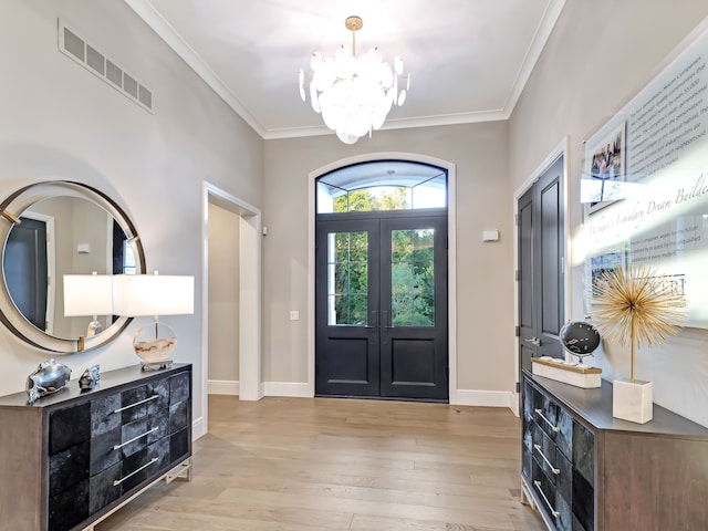 entryway featuring a chandelier, french doors, light wood-type flooring, and ornamental molding