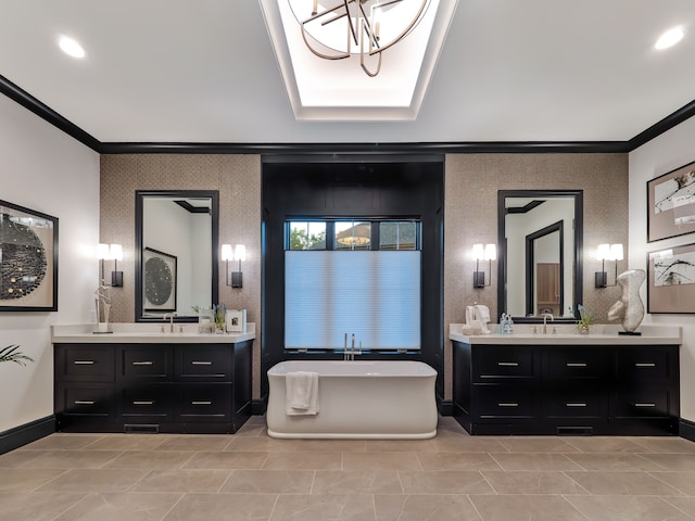 bathroom featuring a chandelier, vanity, a tub to relax in, and ornamental molding