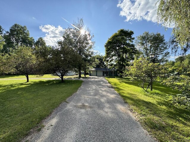 5490 S Harrison Rd, Houghton Lake, MI 48629 - view of property hidden behind natural elements with an attached garage, a front lawn, and asphalt driveway