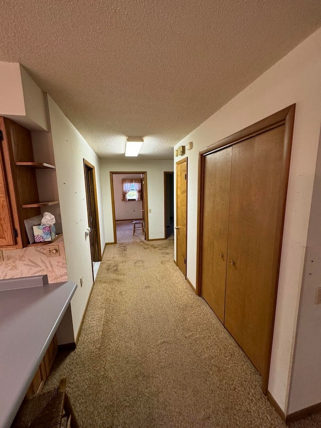 hall with light colored carpet and a textured ceiling