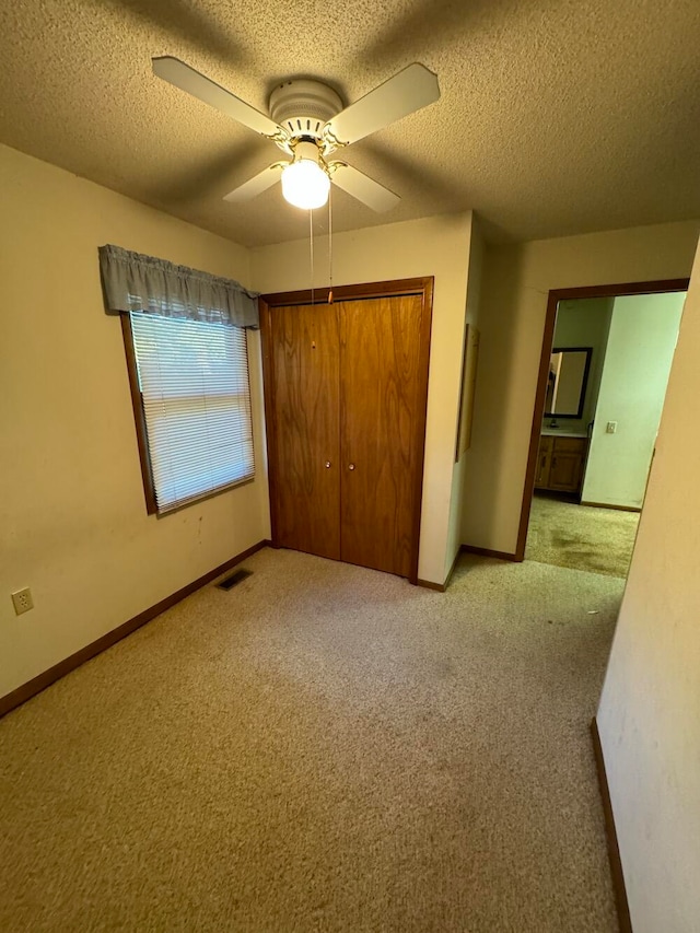 unfurnished bedroom with ceiling fan, a closet, light carpet, and a textured ceiling