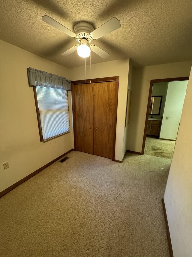 5490 S Harrison Rd, Houghton Lake, MI 48629 - unfurnished bedroom with light carpet, a closet, a textured ceiling, baseboards, and ceiling fan