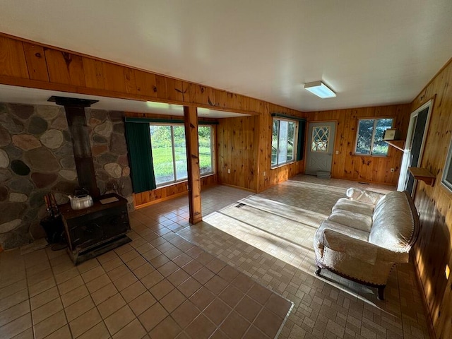 tiled living room featuring a wood stove and wood walls