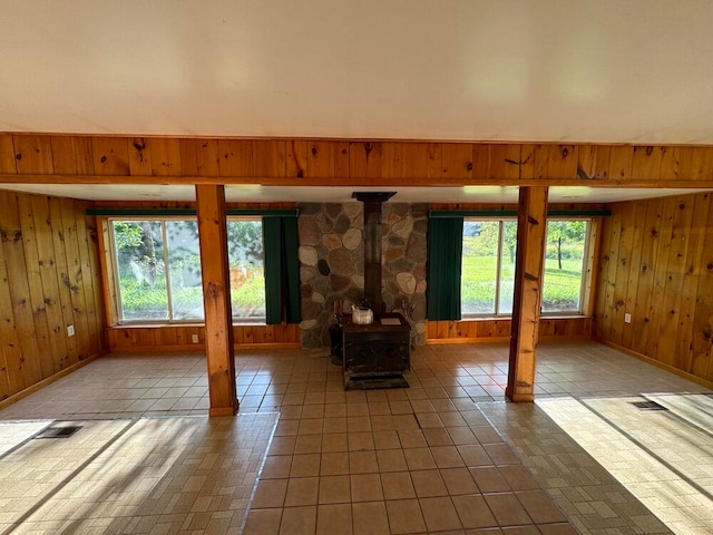 interior space with tile patterned flooring, a wood stove, and wooden walls