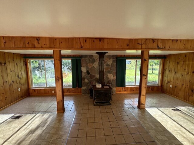 5490 S Harrison Rd, Houghton Lake, MI 48629 - unfurnished living room featuring wood walls, a wood stove, and baseboards