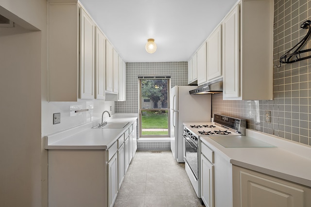 kitchen with decorative backsplash, white appliances, sink, light tile patterned floors, and white cabinetry