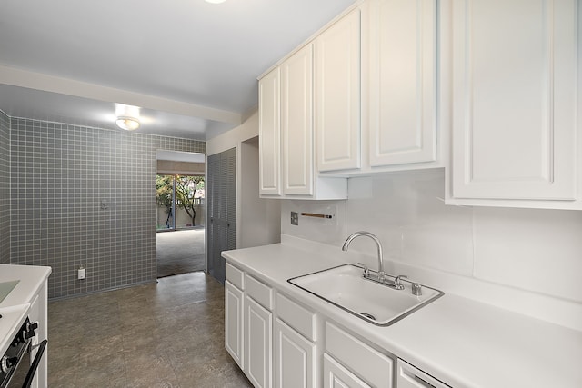 kitchen with white cabinetry, tile walls, and sink