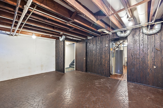 basement featuring wood walls and water heater