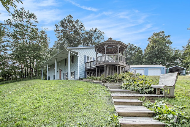 back of house with an outdoor structure, a garage, a yard, and a wooden deck