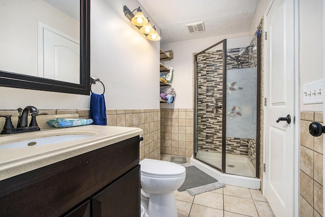 bathroom with an enclosed shower, vanity, a textured ceiling, tile walls, and tile patterned flooring