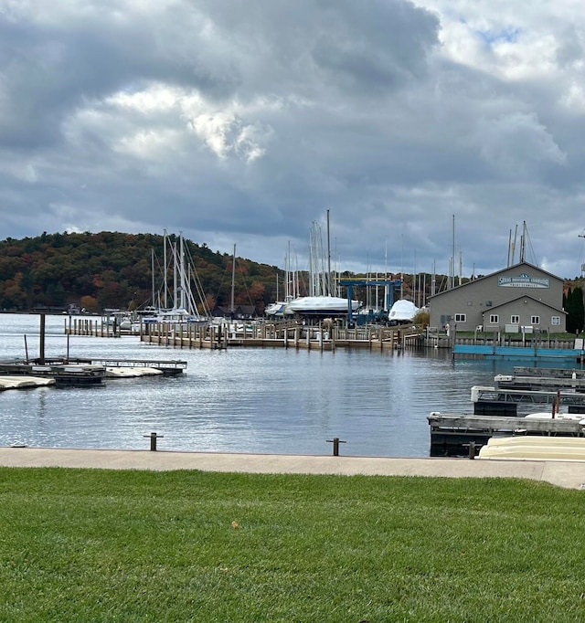 view of dock with a lawn and a water view