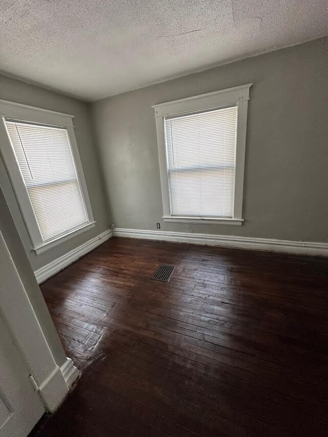 1408 E Main St, Kalamazoo, MI 49048 - empty room featuring dark wood finished floors, a textured ceiling, and baseboards