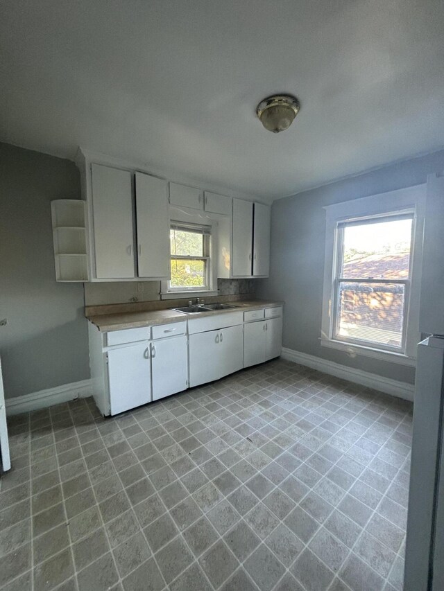 1408 E Main St, Kalamazoo, MI 49048 - kitchen with baseboards, a sink, white cabinets, and light countertops