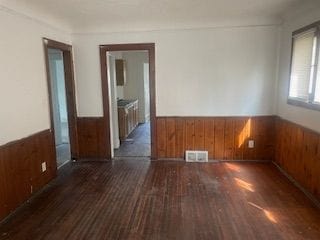 empty room with wood walls and dark wood-type flooring