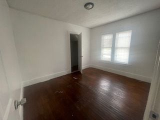 empty room with dark hardwood / wood-style flooring