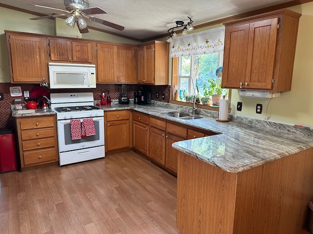 kitchen featuring vaulted ceiling, sink, white appliances, kitchen peninsula, and a textured ceiling