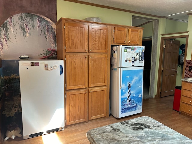 kitchen featuring refrigerator, light hardwood / wood-style floors, white fridge, and a textured ceiling