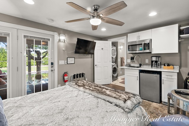 kitchen featuring white cabinetry, sink, stainless steel appliances, light hardwood / wood-style flooring, and stacked washer / dryer