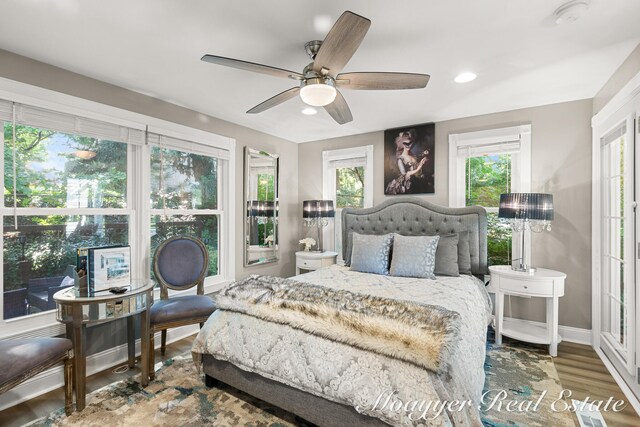 bedroom with hardwood / wood-style floors, ceiling fan, and multiple windows