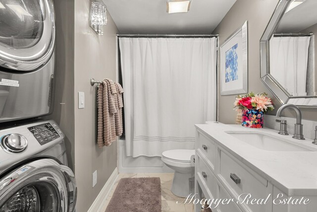 15 E Wall St, Douglas, MI 49406 - bathroom featuring stacked washing machine and dryer, toilet, vanity, marble finish flooring, and baseboards