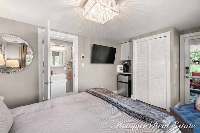 bedroom featuring connected bathroom, stainless steel fridge, and a notable chandelier