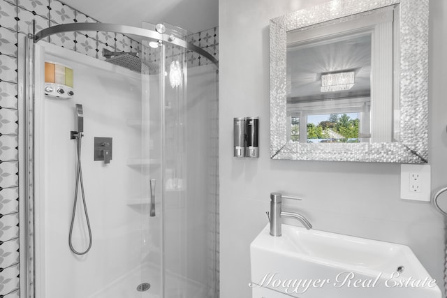 bathroom featuring a shower with shower door and sink