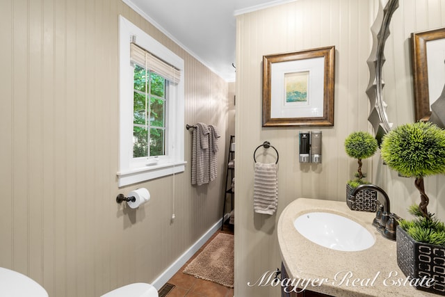 bathroom with tile patterned flooring, vanity, ornamental molding, and wood walls