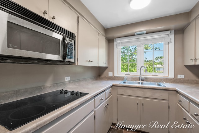 kitchen with white cabinetry, black electric stovetop, and sink