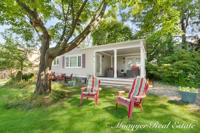 rear view of house featuring a lawn and covered porch