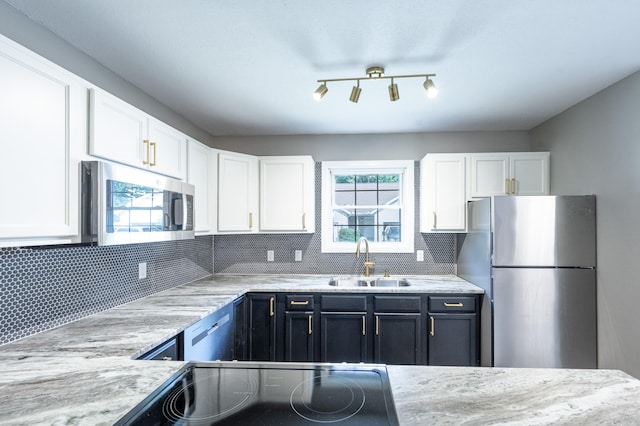 kitchen with sink, light stone counters, backsplash, white cabinets, and appliances with stainless steel finishes