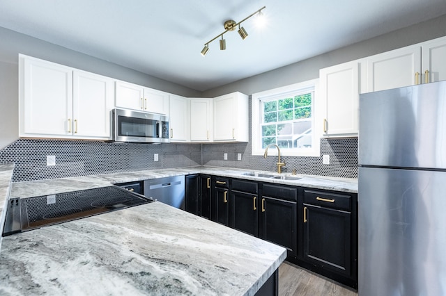 kitchen with appliances with stainless steel finishes, tasteful backsplash, light hardwood / wood-style flooring, and sink