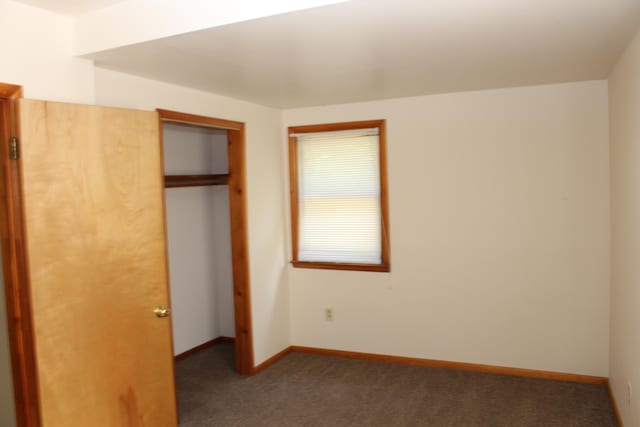 unfurnished bedroom featuring dark colored carpet and a closet