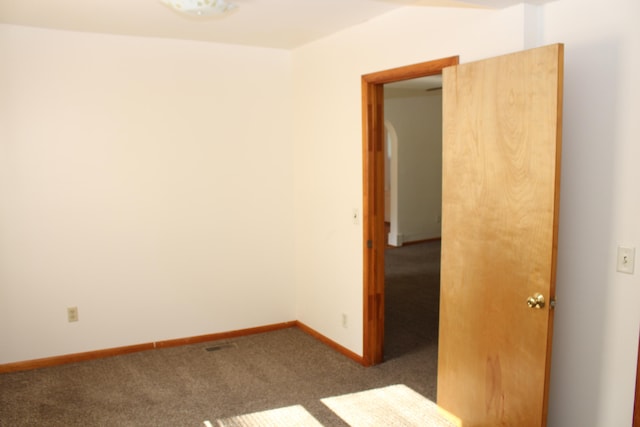 unfurnished room featuring dark colored carpet