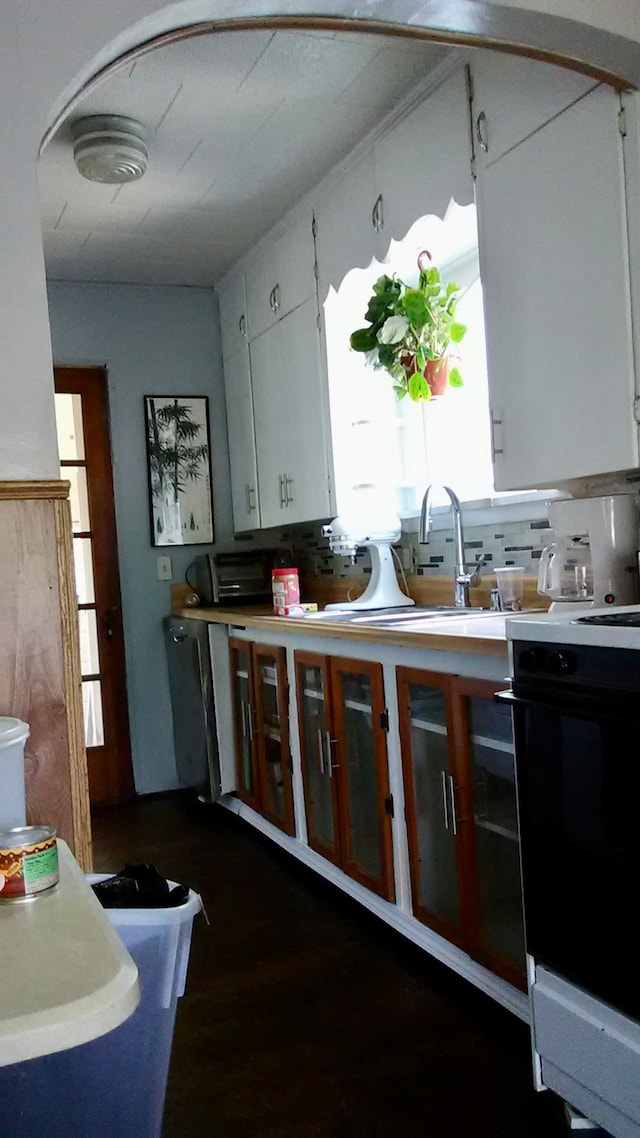1460 S Dye Rd, Flint, MI 48532 - kitchen with white cabinets, electric stove, decorative backsplash, dark wood-type flooring, and light countertops