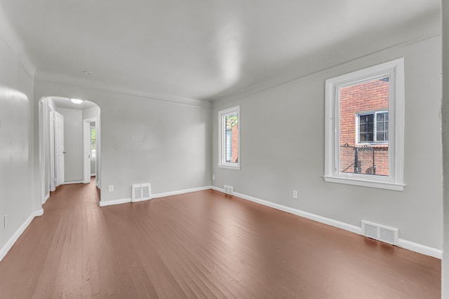 spare room featuring hardwood / wood-style floors, a healthy amount of sunlight, and crown molding