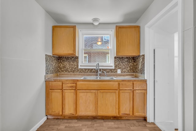 kitchen with backsplash, light wood-type flooring, sink, and light brown cabinetry